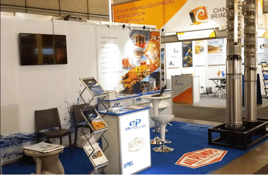 Allied Pumps and All-Pumps exhibition booth at AIMEX, showcasing large industrial pumps and promotional materials.