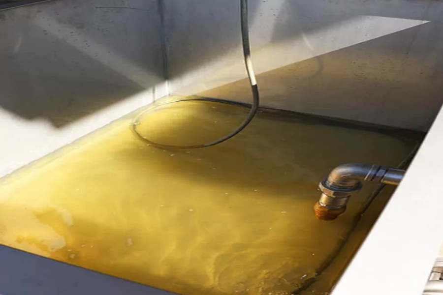 Interior view of a blow down tank partially filled with murky yellow liquid, featuring an inlet pipe and sensor cable at a fuel terminal using an Ebara pump system.