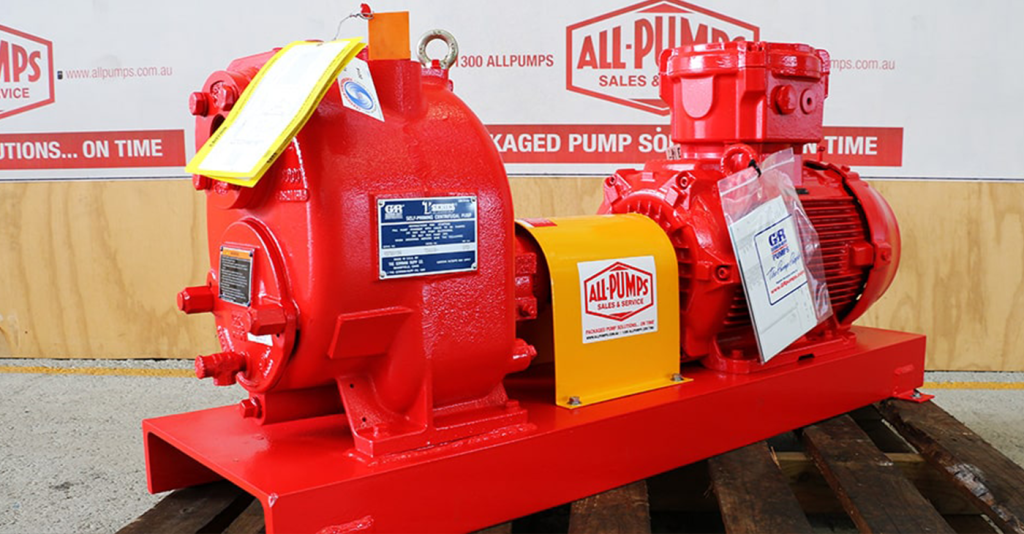 Bright red Gorman-Rupp self-priming centrifugal trash pump coupled to an electric motor, mounted on a skid base for handling slurry, wastewater, and solids in municipal and industrial environments