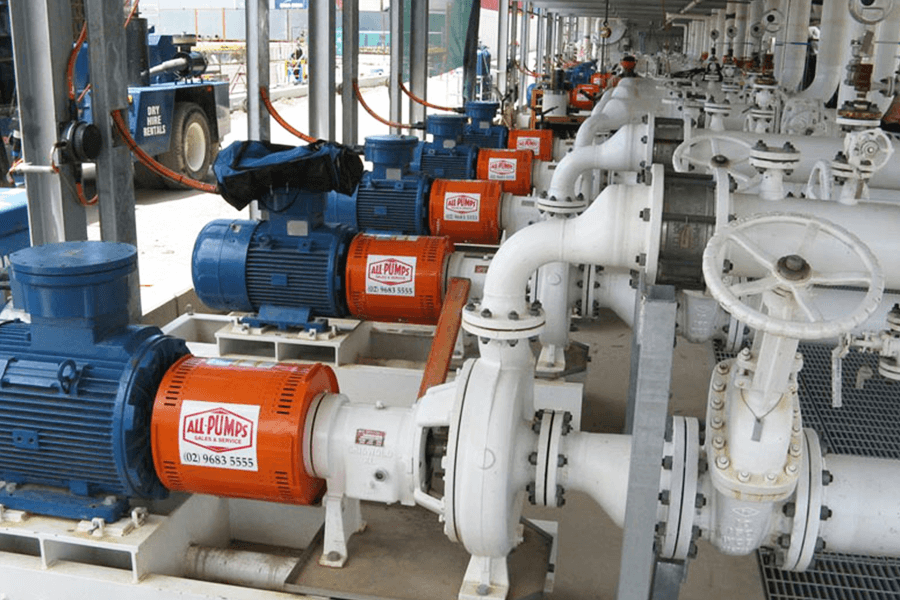 A factory showing pumps with blue and orange pipes, used for various industrial processes.