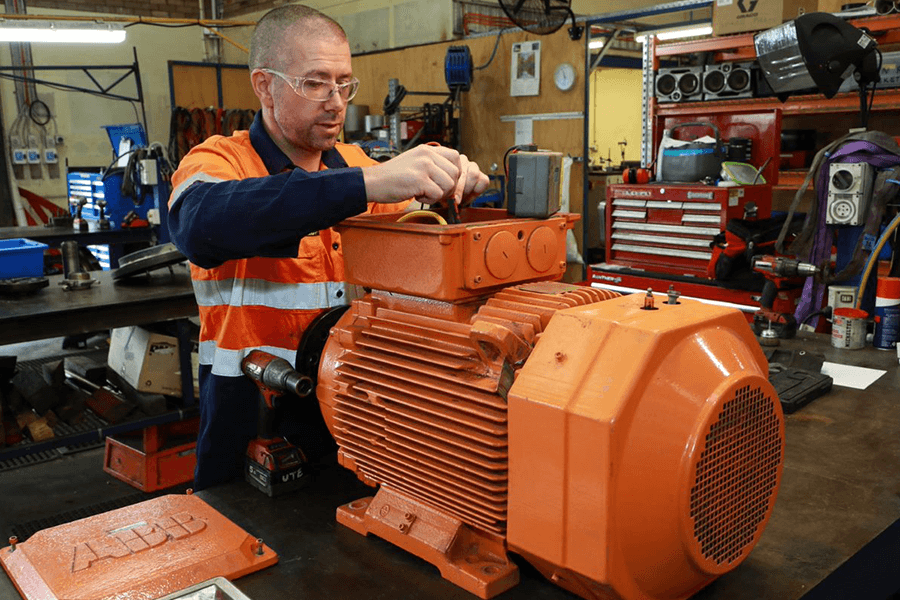 "All Pumps technician working on a large orange motor. "