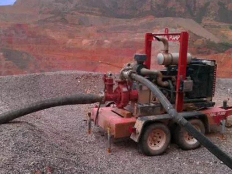 Global Pump Trash Pump operating at a mining site for dewatering. The red trailer-mounted unit is positioned on gravel terrain, efficiently removing water through large suction hoses.