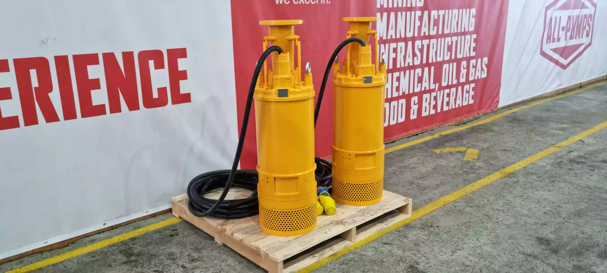 two-yellow-tsurumi-pumps-on-a-pallet-with-a-sign-that-says-experience-at-1000-volt-mine-dewatering-site
