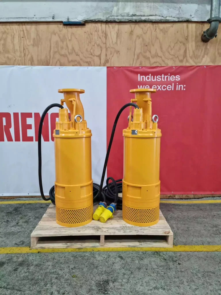 Pair of heavy-duty yellow submersible mining pumps on a pallet, rated for 1000 volt operation and specifically designed for rugged, high-head mine dewatering applications
