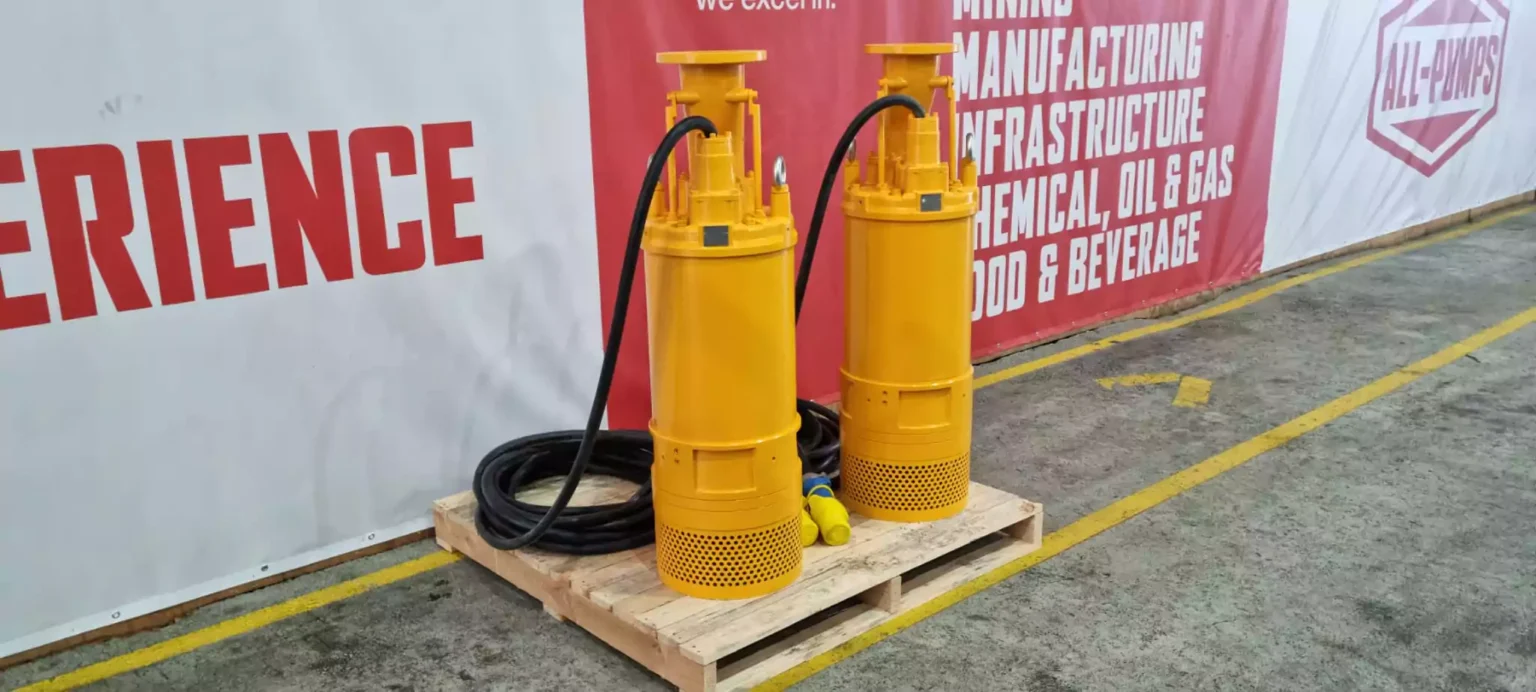 two yellow tsurumi pumps on a pallet with a sign that says experience at 1000 volt mine dewatering site