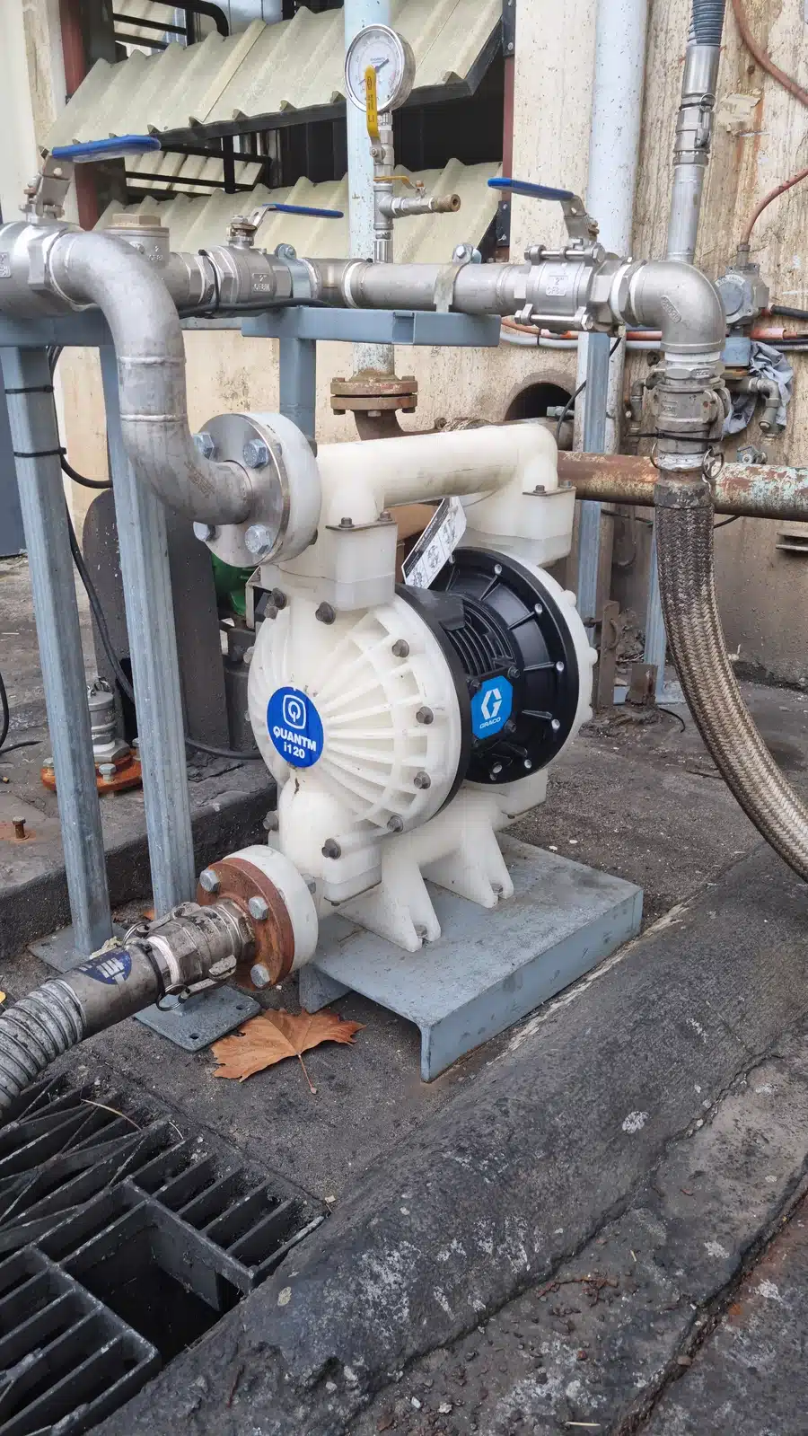 A Graco QUANTM pump placed on the ground adjacent to a pipe