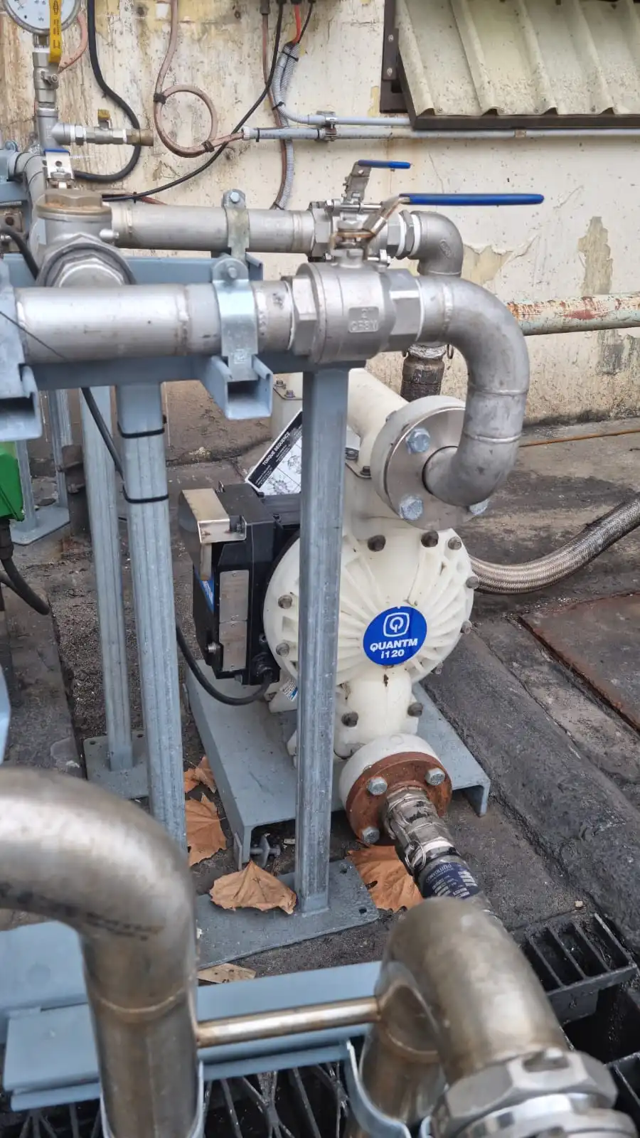 A Graco QUANTM pump resting on the ground next to a pipe