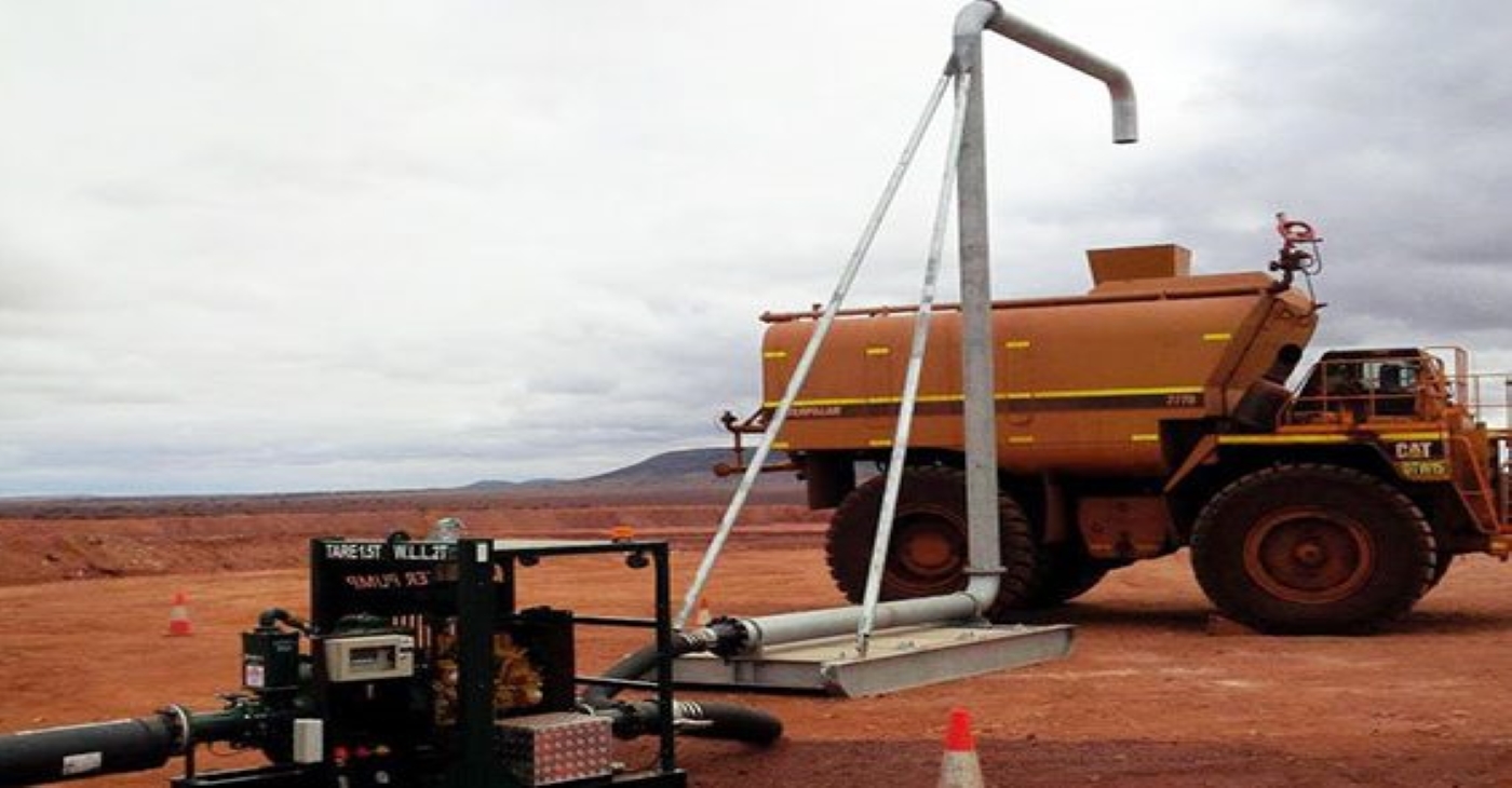 Heavy-duty diesel transfer pumpset on a skid, featuring an electric motor and large piping, used for rapid fluid movement and refilling a heavy industrial water truck at a mine site
