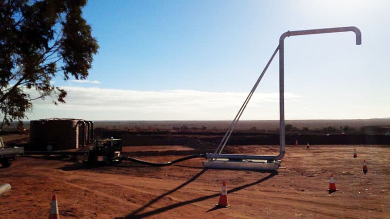 Filling Water Trucks At Mines resting on a dirt road, set against a rural landscape.