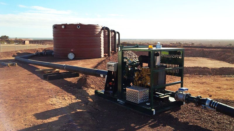 Filling Water Trucks At Mines on a dirt field, with no vegetation visible in the surrounding area.