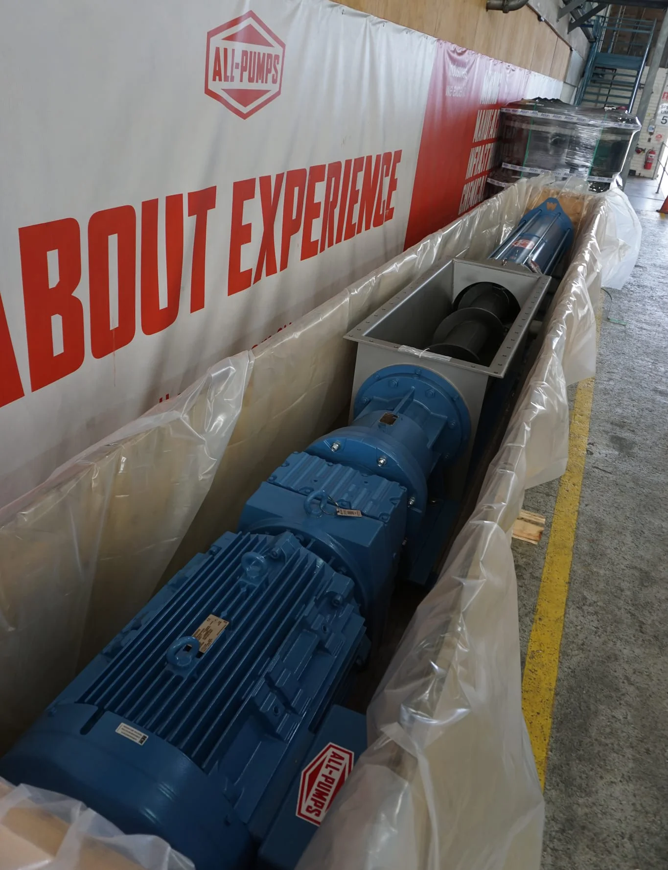 Wangen industrial helical rotor pump in blue, placed in protective packaging at an All-Pumps facility. The pump features a robust motor and gearbox assembly, designed for heavy-duty industrial fluid handling and viscous material transfer applications.