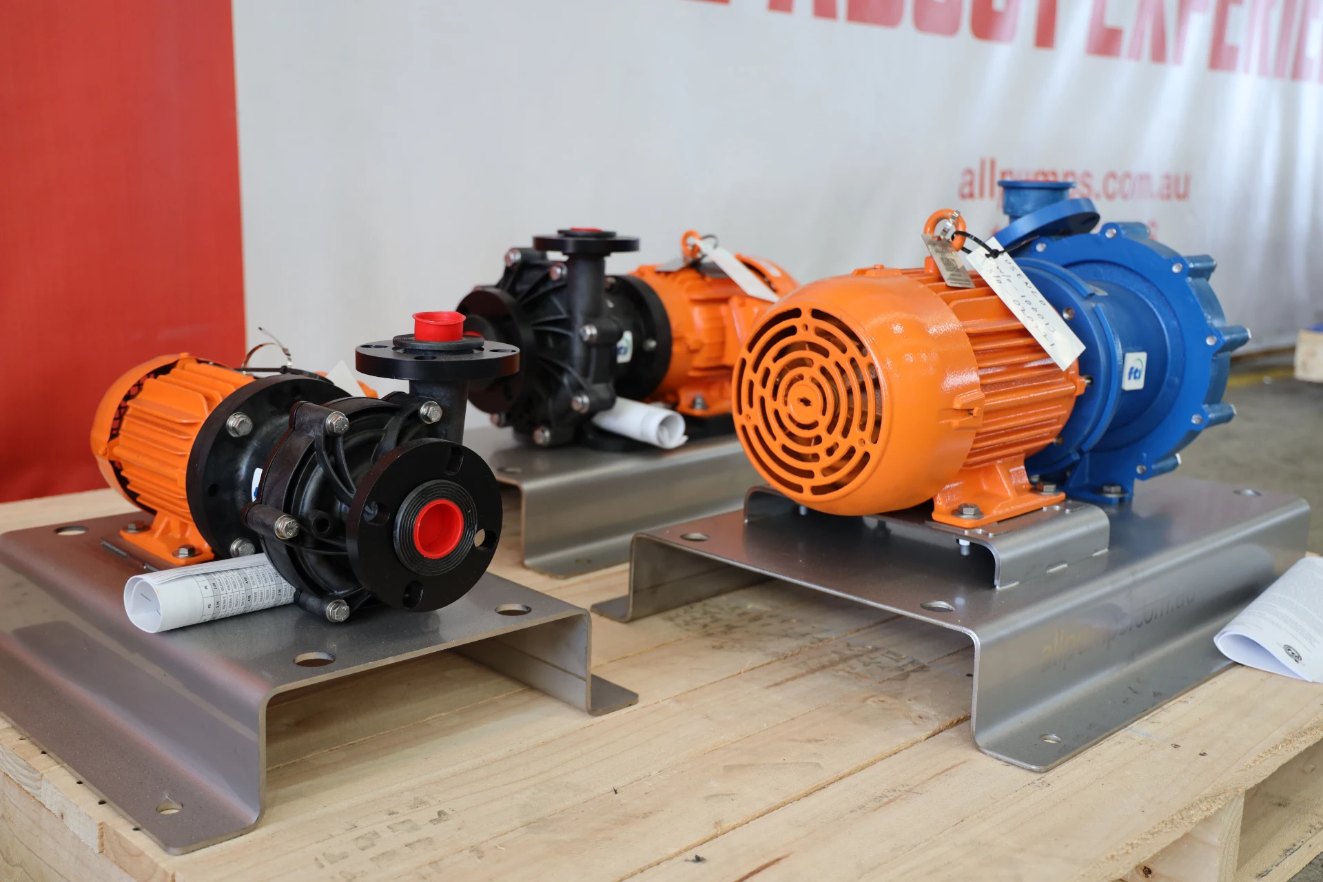 Three orange and black Finish Thompson industrial pumps mounted on stainless steel skids, featuring centrifugal and chemical transfer models.