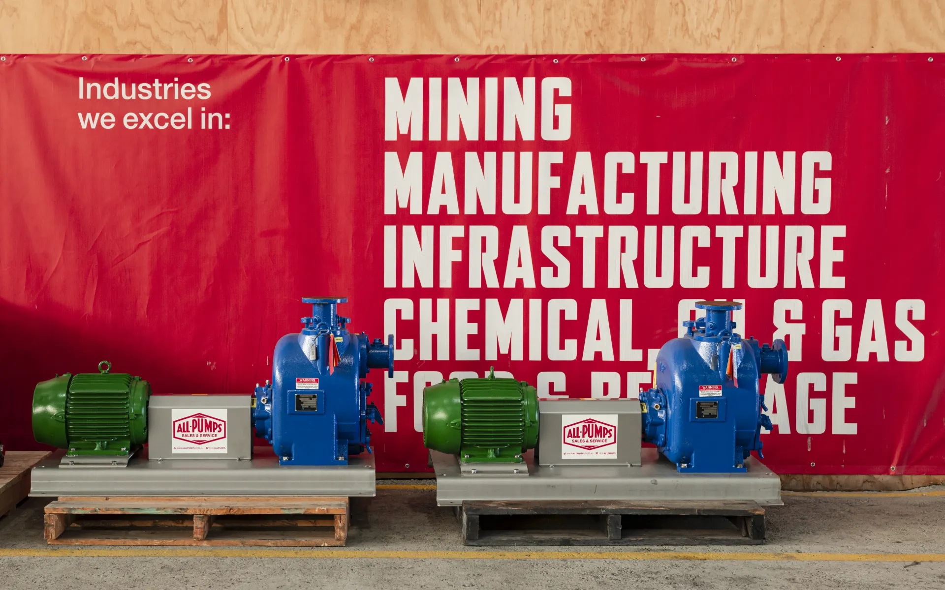 Exhibition setup featuring Trillium WSP pumps on steel bases with All-Pumps signage, in front of a red banner highlighting key industries like mining and infrastructure.
