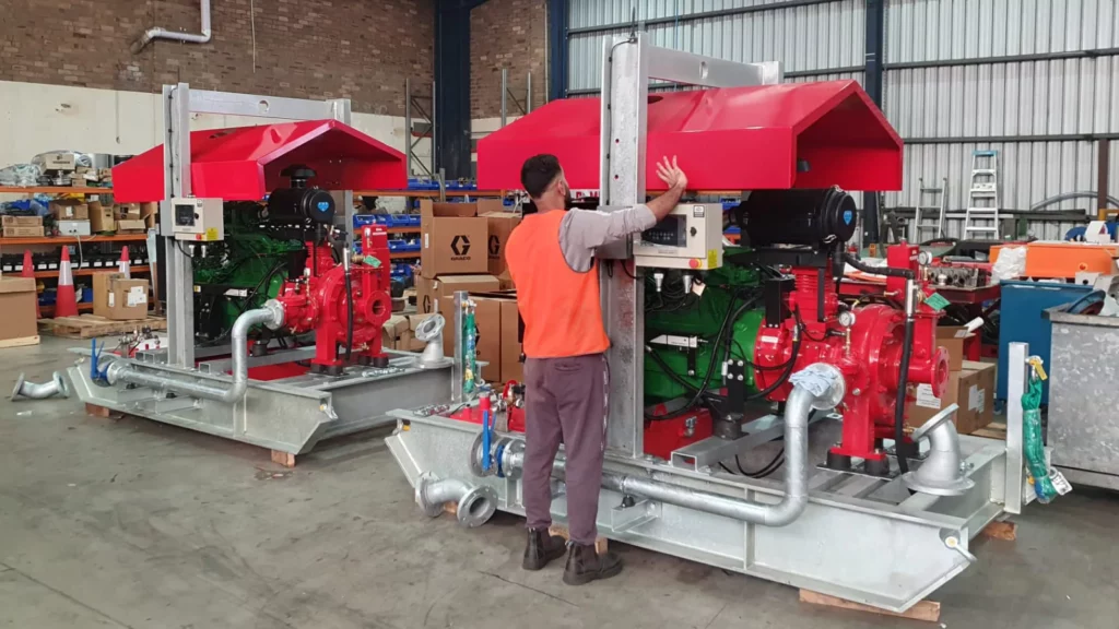 Worker beside a large red custom dewatering pump set