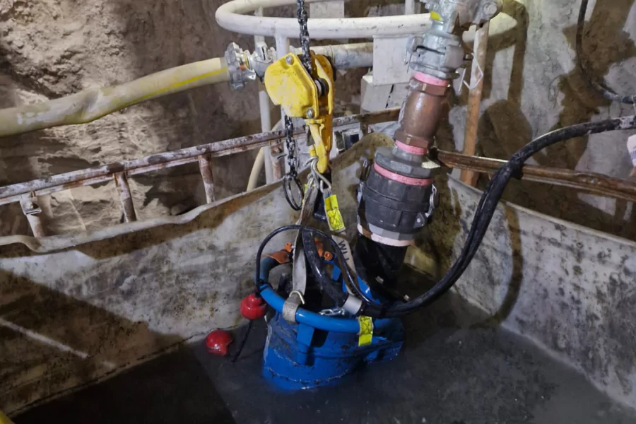 Worker inspecting a pump beside underground piping